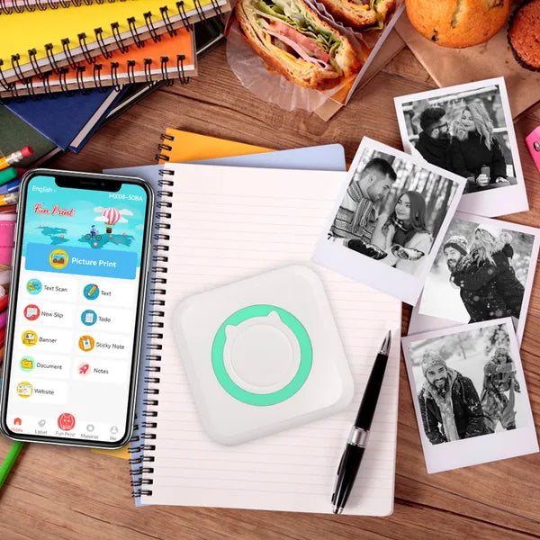 PocketLabel printer on a desk with the phone app open and printed photos alongside