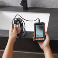 VEVOR dual-lens borescope inspection camera held in one hand with the probe extended